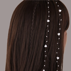 Détail d'une chaîne de cheveux en perles avec breloques cœur tressée dans une coiffure