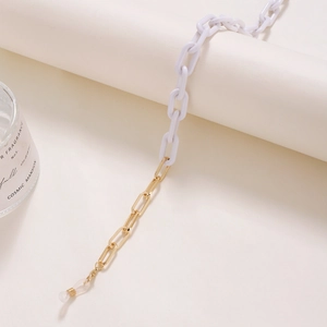 Minimalist white acrylic and gold metal chain for glasses or masks on a white pedestal