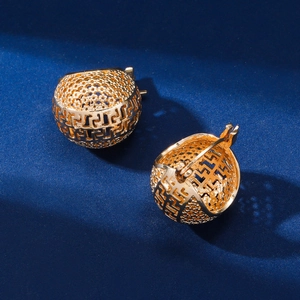 Vue macro de boucles d'oreilles sphériques ajourées en or avec motifs géométriques