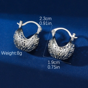Detailed macro view of silver hollow geometric mesh hoop earrings on blue velvet background