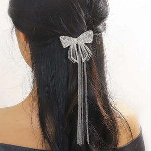 Barrette à cheveux nœud argenté avec de longs glands en chaîne sur cheveux foncés