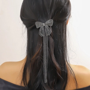 Barrette nœud en strass étincelants avec longues franges sur cheveux ondulés noirs