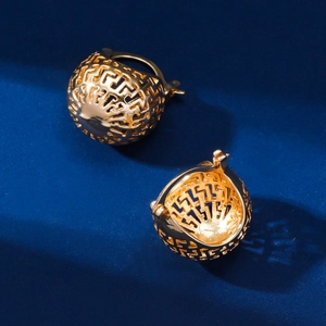 Detail of gold hollow spherical earrings featuring intricate Greek key pattern engravings