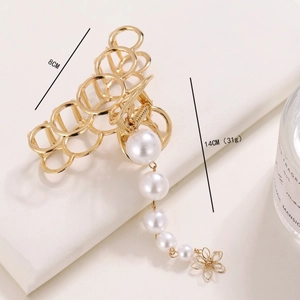Vue détaillée d'une pince à cheveux dorée de 8cm avec perles et pendentif fleur