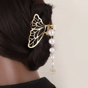 Détail d'une pince à cheveux papillon dorée avec un élégant gland en perles sur cheveux