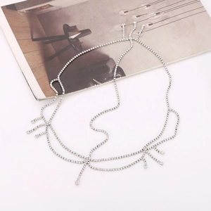 Flat lay of silver fringe hair chain with rhinestones on a white surface with magazine