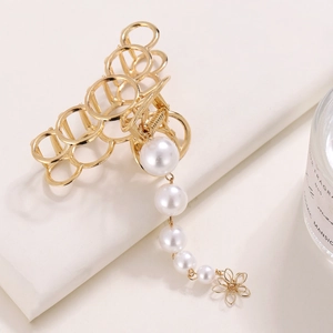 Gros plan d'une pince à cheveux dorée avec des perles pendantes et un pendentif floral