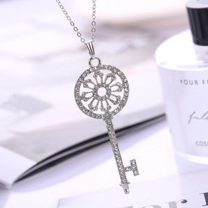 Close-up of a silver key pendant necklace with sparkling crystal inlay and hollow pattern
