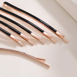 Detailed close-up of minimalist rose gold and black enamel bobby pins in a radial layout