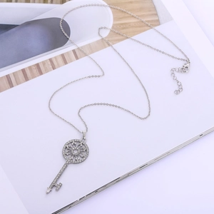 Detail of silver key pendant with sunwheel design and sparkling pavé set rhinestones