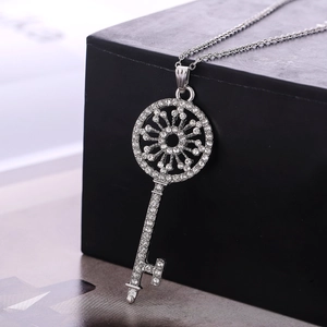 Detailed view of a silver key pendant necklace with sparkling rhinestones on a display box