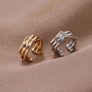 Detail von U-förmigen gewebten Ohrmanschetten in Gold und Silber auf Stoffhintergrund