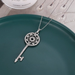 Retro Roman key pendant necklace with white zircons and silver chain on ceramic plate