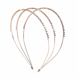 Détail de trois serre-têtes en or rose sertis de strass brillants sur fond blanc épuré