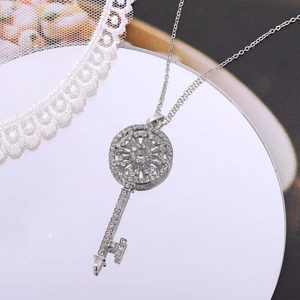 Silver key pendant necklace with crystals and rhinestones on a mirror surface