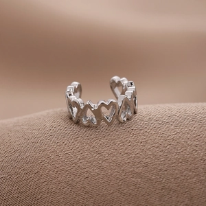 Minimalist silver heart ear cuff with hollow design on champagne satin fabric