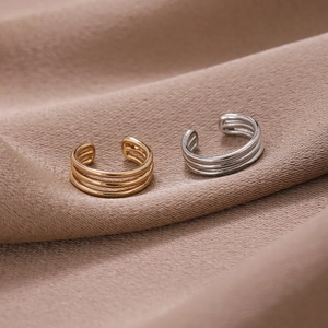 Detail von silbernen und goldenen minimalistischen Ohrklemmen auf Seidenhintergrund