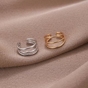 Minimalistische U-förmige Ohrmanschetten in Gold und Silber auf Seidenhintergrund