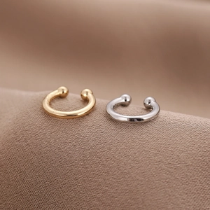 Makroansicht minimalistischer U-förmiger Ohrmanschetten in Gold und Silber auf Stoff