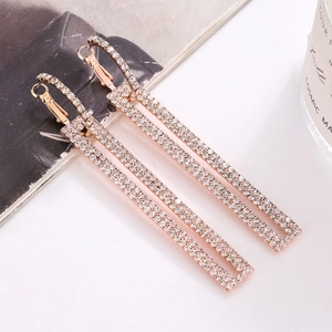 Sparkling rose gold rectangular drop earrings with crystal pavé on a dark background