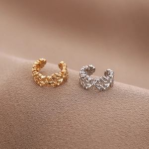 Nahaufnahme goldener und silberner Gänseblümchen-Ohrklemmen auf braunem Stoff