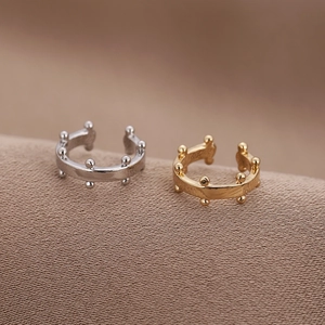 Makroansicht minimalistischer goldener und silberner U-förmiger Ohrklemmen mit Kugeln