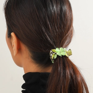 Dettaglio di un fermaglio per capelli a tulipano verde indossato su una coda di cavallo