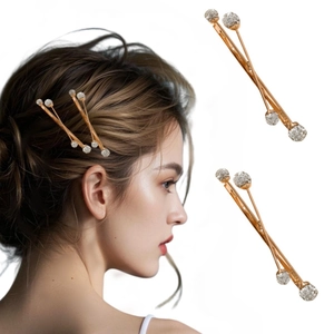 Detail view of gold alloy cross hair clips with rhinestones on an Asian female model