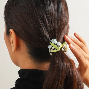 Dettaglio del fermaglio per capelli mughetto su coda di cavallo con perle e metallo