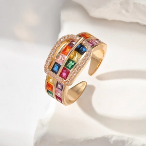Macro detail of gold buckle ring with vibrant rainbow square-cut zircons on a white stone