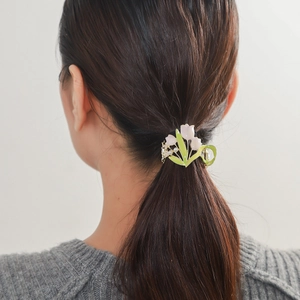 Dettaglio della clip per capelli a forma di mughetto rosa con perle su acconciatura