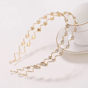 Elegant gold wavy rhinestone headbands set on a white cup, minimalist hair accessories