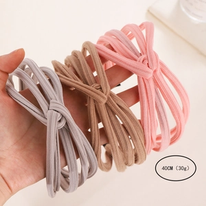 Three-piece set of knitted knot headbands in pastel shades of purple, brown, and pink