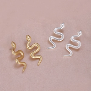 Boucles d'oreilles serpent mates or et argent sur un tissu en soie élégant