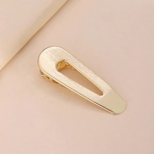 Detail of gold hollow teardrop hair clip featuring a brushed metal texture and spring clasp