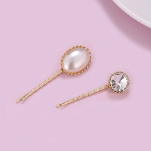 Elegant gold hair clip set with white pearl and sparkling crystal on purple background