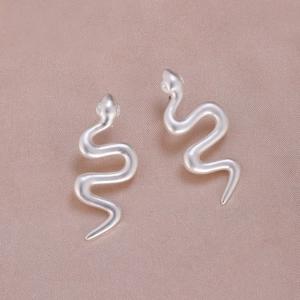 Boucles d'oreilles serpent argent mat minimalistes sur fond de soie rose élégant