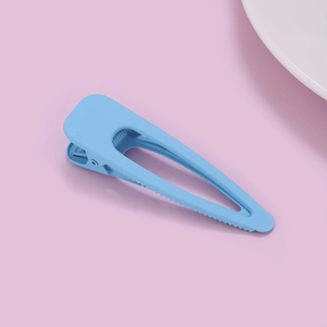 Detail of light blue matte finish hair clip on a pink background with ceramic dish