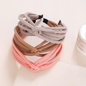 Close-up of three knotted fabric headbands in grey-purple, brown, and light pink colors