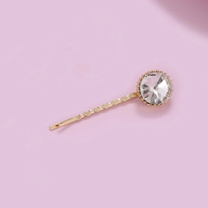 Detailed view of wave-shaped gold hairpin with large sparkling round rhinestone crystal