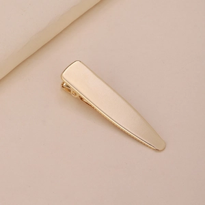 Barrette à cheveux bec de canard en métal doré poli sur un fond crème élégant