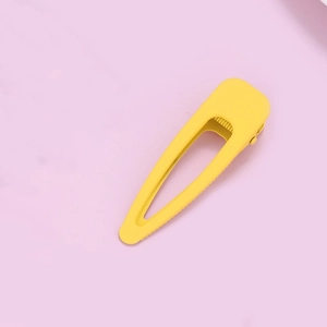 Macro detail of a bright yellow matte finish duckbill hair clip on a purple background