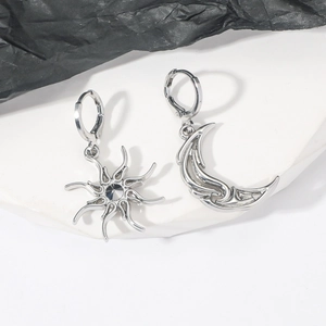 Detail view of asymmetric sun and moon drop earrings with a central dark gemstone
