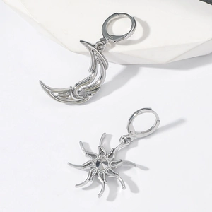 Macro detail of asymmetric sun and moon earrings with hollow outlines and zircon inlay