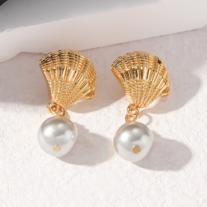 Détail de boucles d'oreilles coquillage en argent s925 doré avec perles blanches
