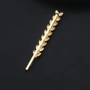 Close-up of golden leaf hair clip featuring intricate wheat ear patterns on black leather