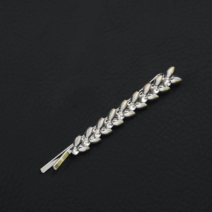 Detailed view of silver leaf bobby pin with sparkling rhinestones on black leather background