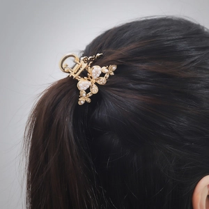 Gros plan d'une pince à cheveux papillon dorée avec perles blanches sur cheveux noirs