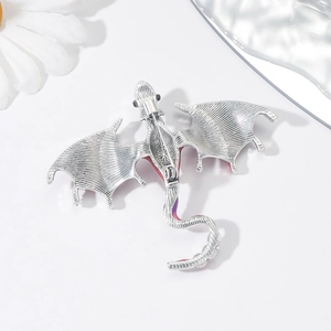 Detailed macro view of vintage dragon brooch with intricate silver metallic textures and pin