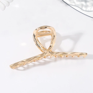 Makro-Detail der großen goldenen Metall-Haarklammer mit gedrehtem hohlem Design-Stil